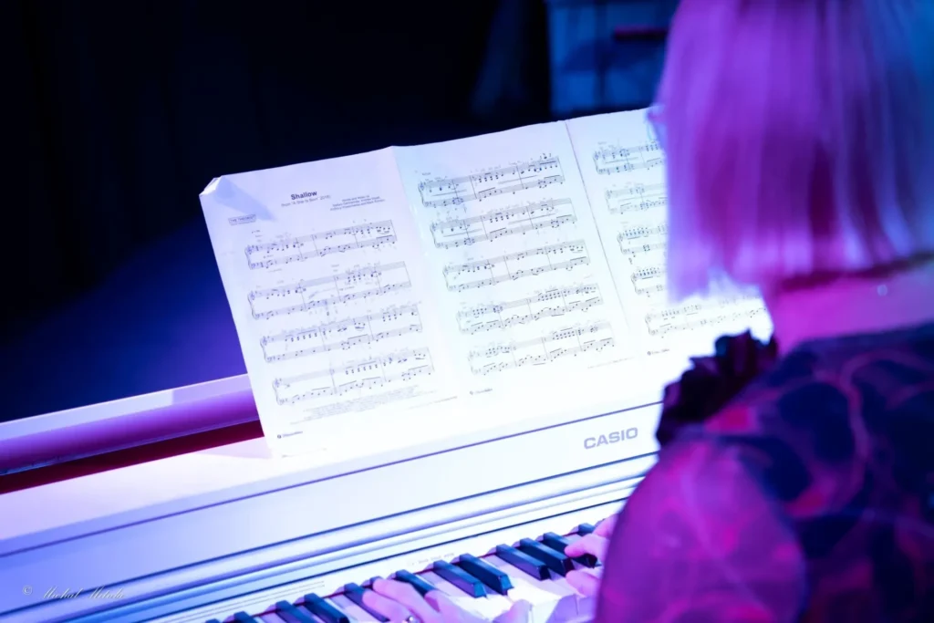 kobieta grająca na pianinie patrząca na nuty